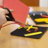 close up of hands cutting red and yellow craft materials