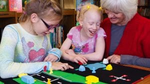 kids and a teacher learning with a tactile neighborhood map