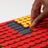A woman's hand turning a yellow dot over to reveal the red side.