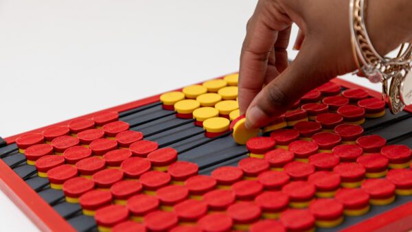 A woman's hand turning a yellow dot over to reveal the red side.