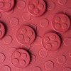The textured side of the red mat with circular red alphabet tiles scattered on top.