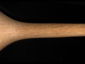 Wooden eraser with one flat side on handle and narrow wooden tip on a black background.