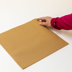 A woman wearing a magenta shirt with her index finger placed on one corner of the brown Swail Dot Inverter Rubber pad.