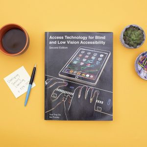Image of book on table surrounded by coffee cup and plant.