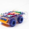 side view of RC Snap rover, a bread board covered in snap circuits pieces sitting on a frame with wheels.