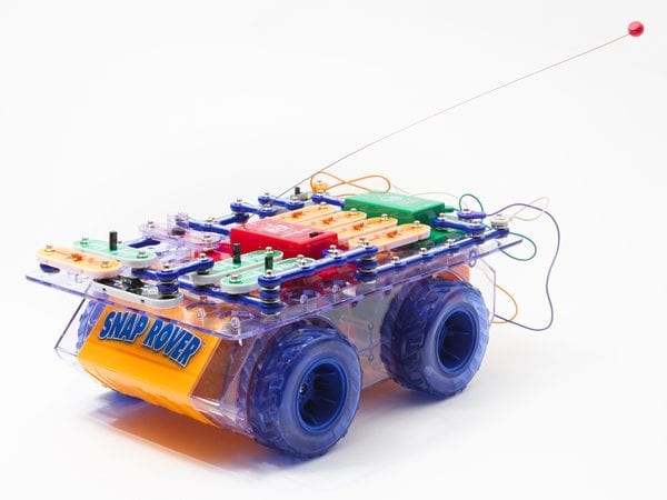 side view of RC Snap rover, a bread board covered in snap circuits pieces sitting on a frame with wheels.