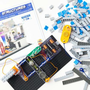 An aerial view of a light-emitting BRIC: Structures project built on a base plate. In the background is the BRIC: Structures box and an assortment of building blocks.