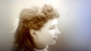 Studio photo of a young girl, about 10. Her hair has been styled with fluffy bangs and long curls.