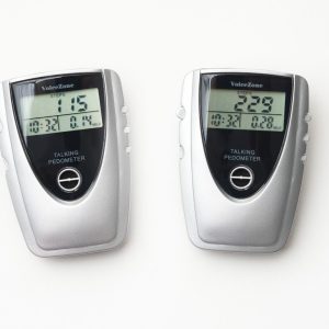 Two, white and black, walking pedometers on a white background. The pedometer on the left shows 115 steps, 0.14 miles walked, and a duration of 10 minutes and 32 seconds. The pedometer on the right, shows 229 steps, 0.28 miles walked, and a duration of 10 minutes and 32 seconds.