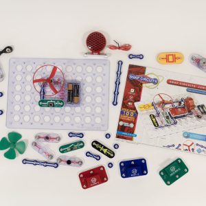 Each Snap Circuits Jr. 130 Access Kit part is displayed over a white background. An exercise is built on the breadboard showcasing the green power switch, one blue # 3 connector piece, a red fan, and two AA batteries inside a clear battery holder.