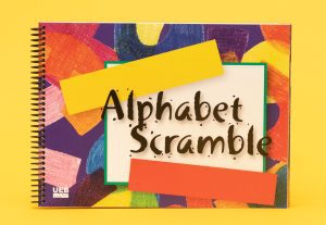 Cover of Alphabet Scramble with UEB icon in the bottom left. The cover contains a variety of colorful graphic shapes that look like crayon drawings beneath a white box containing the title