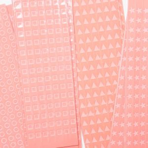 Close up of overlapping perforated shape strips including circles, squares, triangles, and stars.