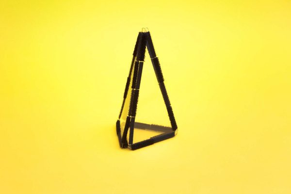 Three isosceles triangle pieces with black Velcro borders connected to one another and an equilateral triangle piece to form a triangular pyramid.