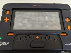 The Monarch displaying a tactile graphic that depicts a row of chess pieces.