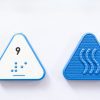 Close up comparison of the front and back of a blue triangular UEB Reach and Match number tile showing the number 9 in braille and print. The back of the piece is textured.