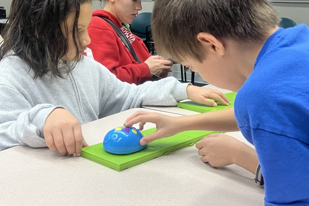 close up of two kids touching Code and Go Mouse on the track