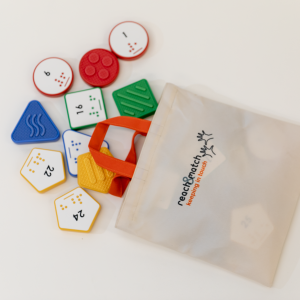 Reach & Match Number Tiles bag filled with multicolored Number Tiles that are spilling out across a white surface. 