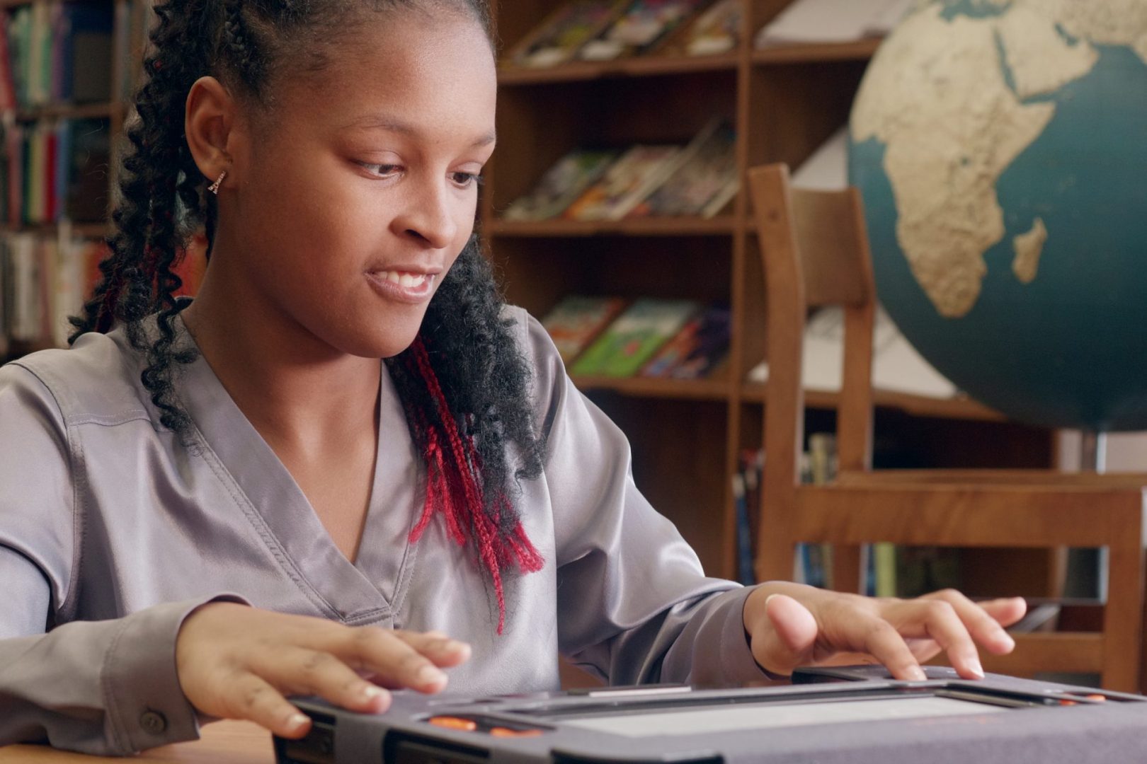 A student sits at a desk, hands on the monarch exploring the navigation buttons.
