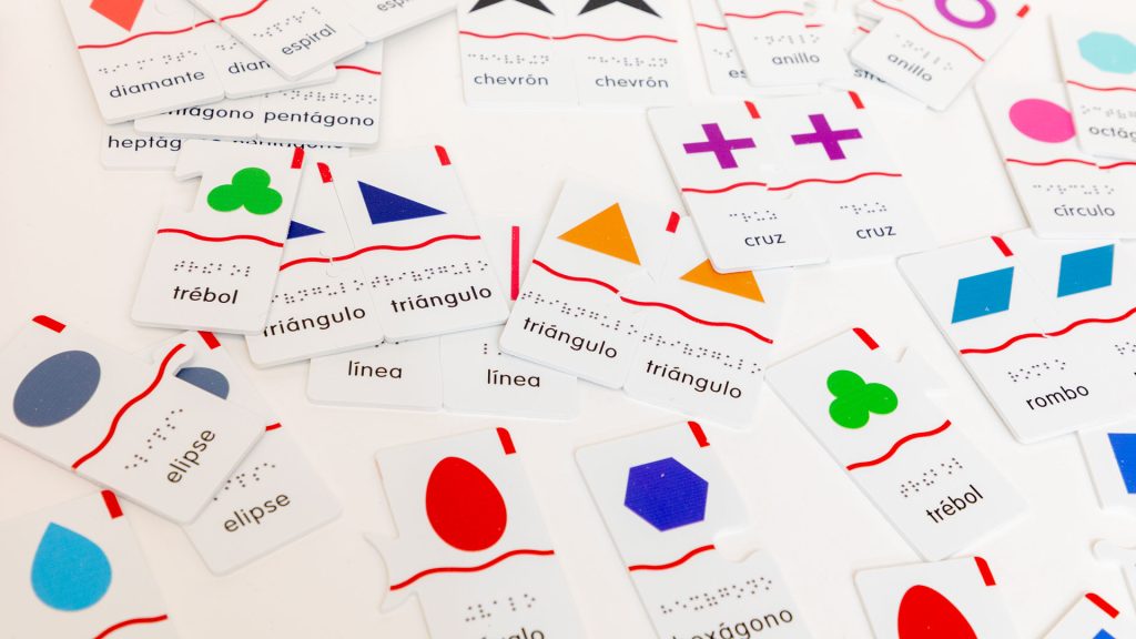 A variety of spanish Memory Puzzles: Shapes pieces scattered on a white surface. Some of the pieces are paired.