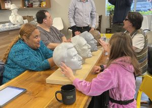 4 individuals who are blind feel 3-D facial statues.