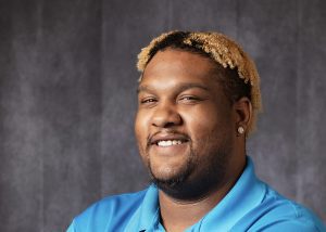 Dimetre, wearing a blue APH polo, smiles at the camera.