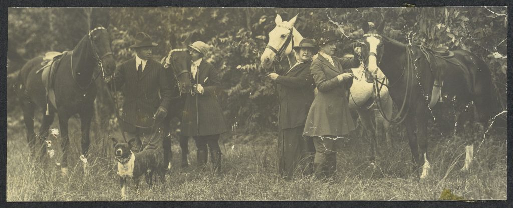 Helen Keller and companions standing next to their horses before horseback riding.