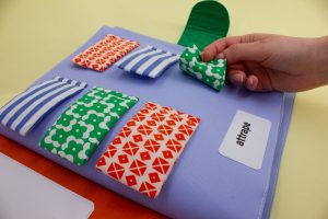 A book cover made of soft material, has small fabric interactive flaps that are being moved by a small hand.