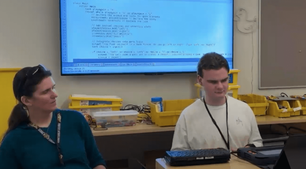 Gina sits next to a student who is using a Monarch as they present on the device.