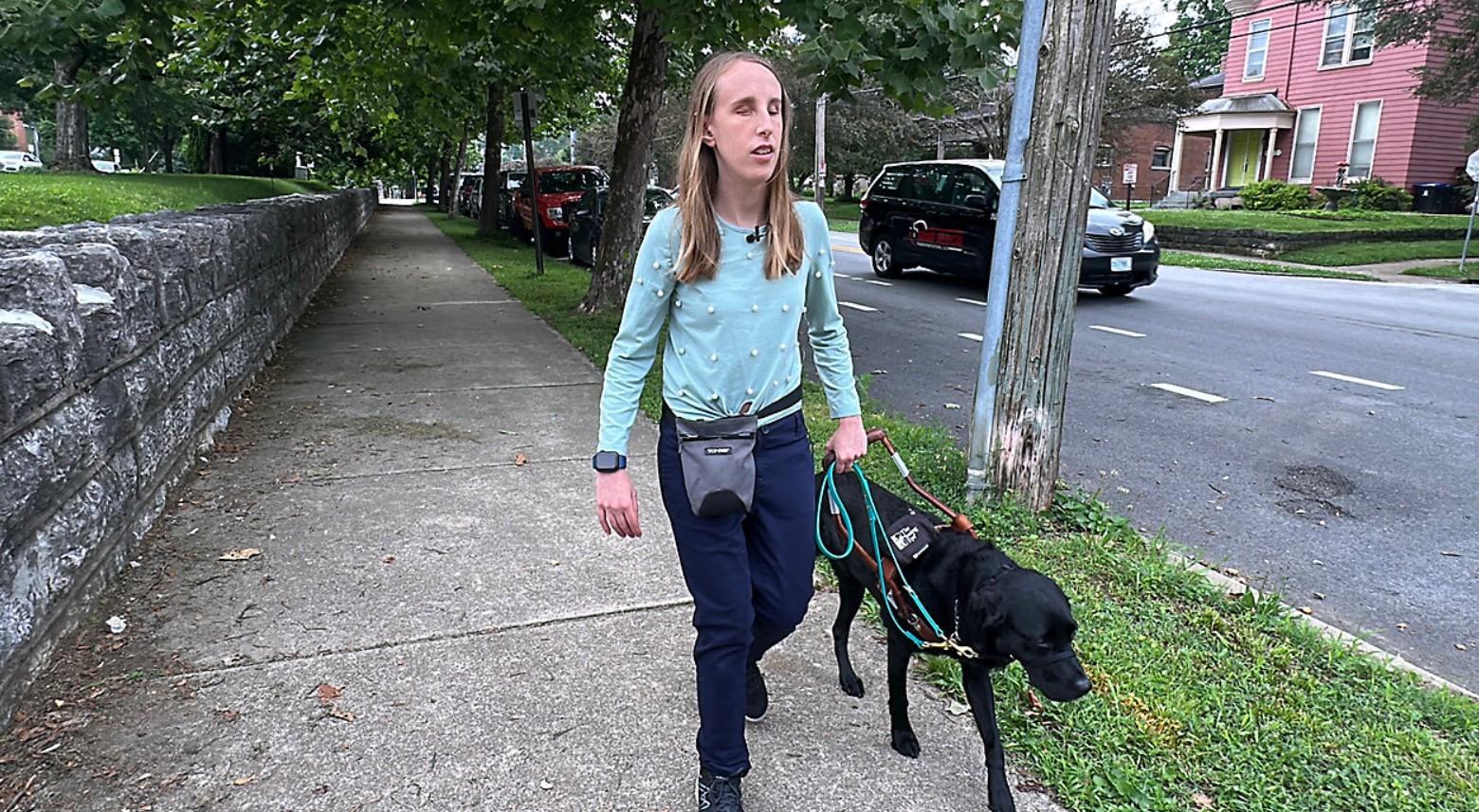A screengrab from Spectrum News 1. Danielle walks down Frankfort Ave. with Violet, her dog guide