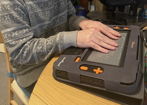 Scott sits at a table and uses his Monarch.