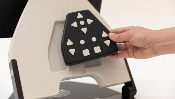 A woman's hand is returning the black Neptune keypad into the recess on the back of the device where a magnet holds it in place.