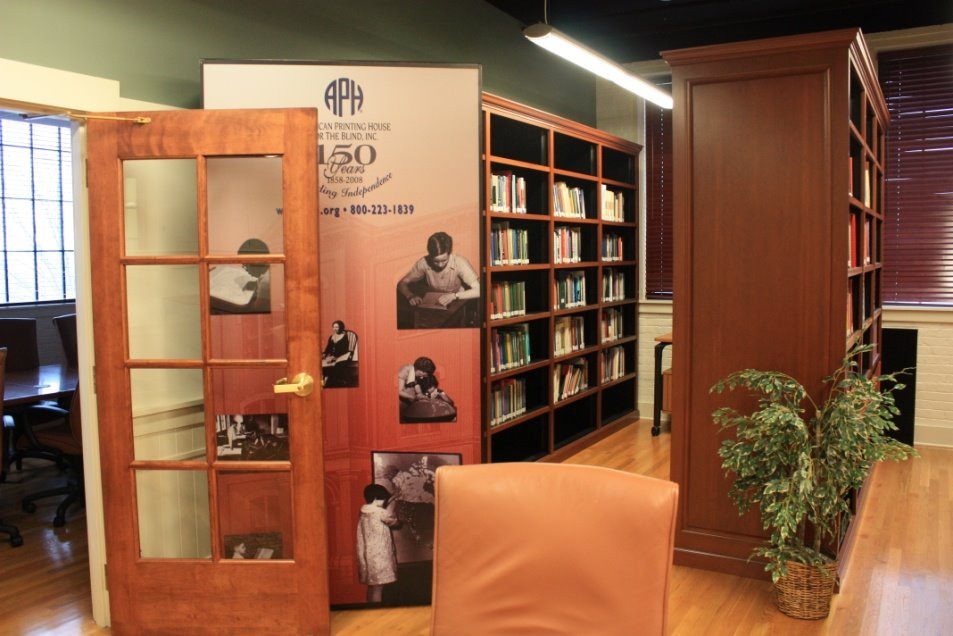 The APH library room, showing bookcases, and a large sign that is celebrating 150 years of APH.