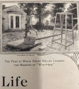 Newspaper image of water pump in front of house. The image has been cropped from the original and there is type set underneath that says "THE PUMP AT WHICH HELEN KELLER LEARNED THE MEANING OF "W-A-T-E-R". 