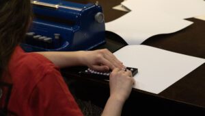 A student uses her Abacus against a piece of paper a table.