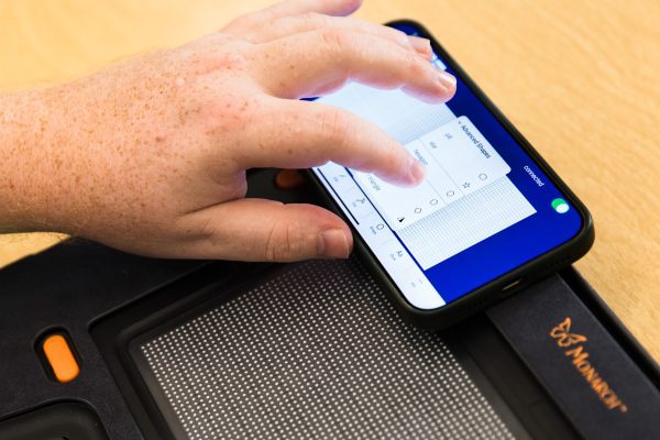 A man is navigating the shape menus on Wing It on his iPhone, which is balanced on the top corner of his Monarch.