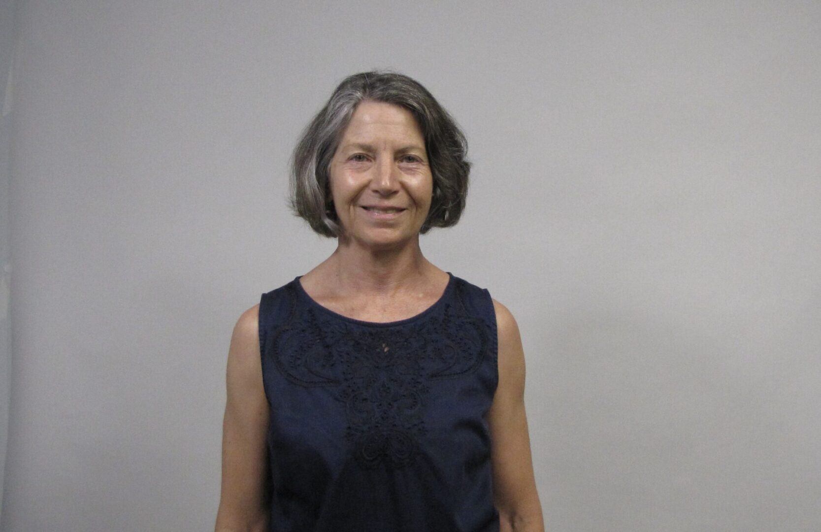 Rosanne smiles at the camera, standing in front of a grey background.