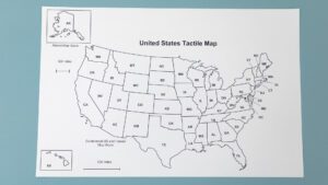 A raised-line black and white paper map of the United States with braille labels on a blue background.