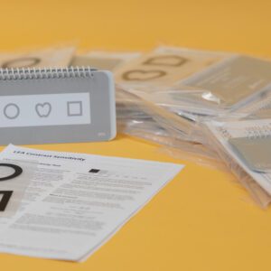 All the components included in the Contrast Sensitivity Kit laid out on a gold background.