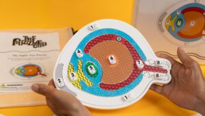 Two hands holding an unlabeled and colorful tactile graphic of an anatomical model of an eye.