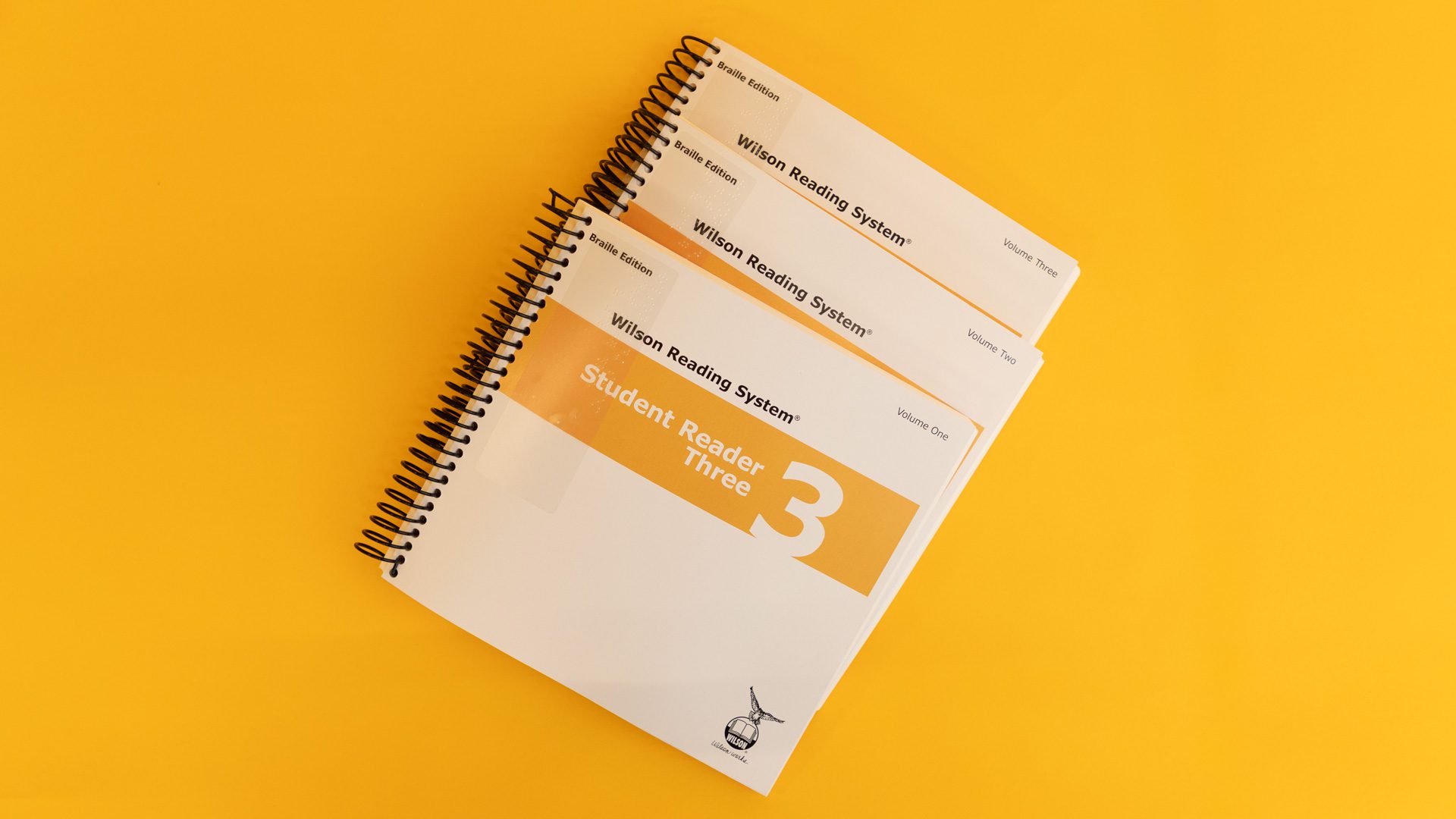 WRS-Braille-Student-Reader-3_4Z9A1239-web Volumes 1, 2, and 3 of the braille student reader 3 with a yellow stripe across all three covers.