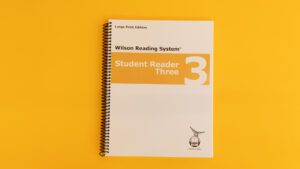 The large print edition of the WRS student reader three with a yellow stripe across the cover.
