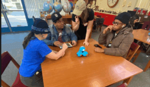 Four adults sit around a table with code jumper modules in the middle of the table.