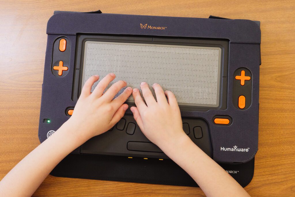 Two hands reach out to read on the Monarch display.