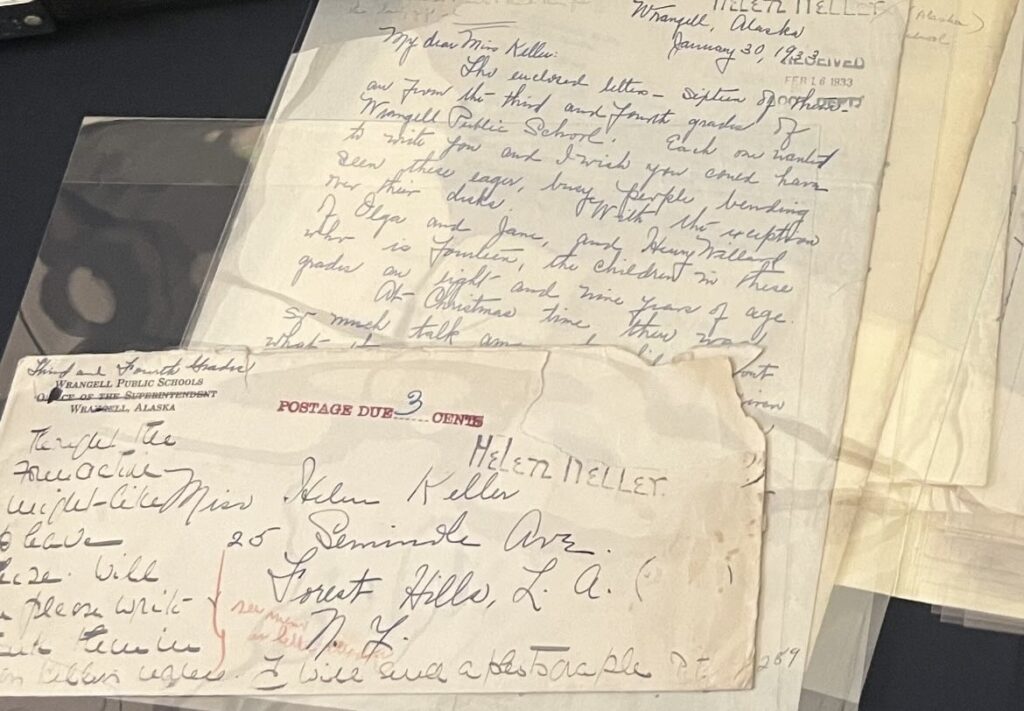 Protected written letters in clear sleeves. The brown paper and cursive writing shows old age. The signature of Helen Keller is visible.