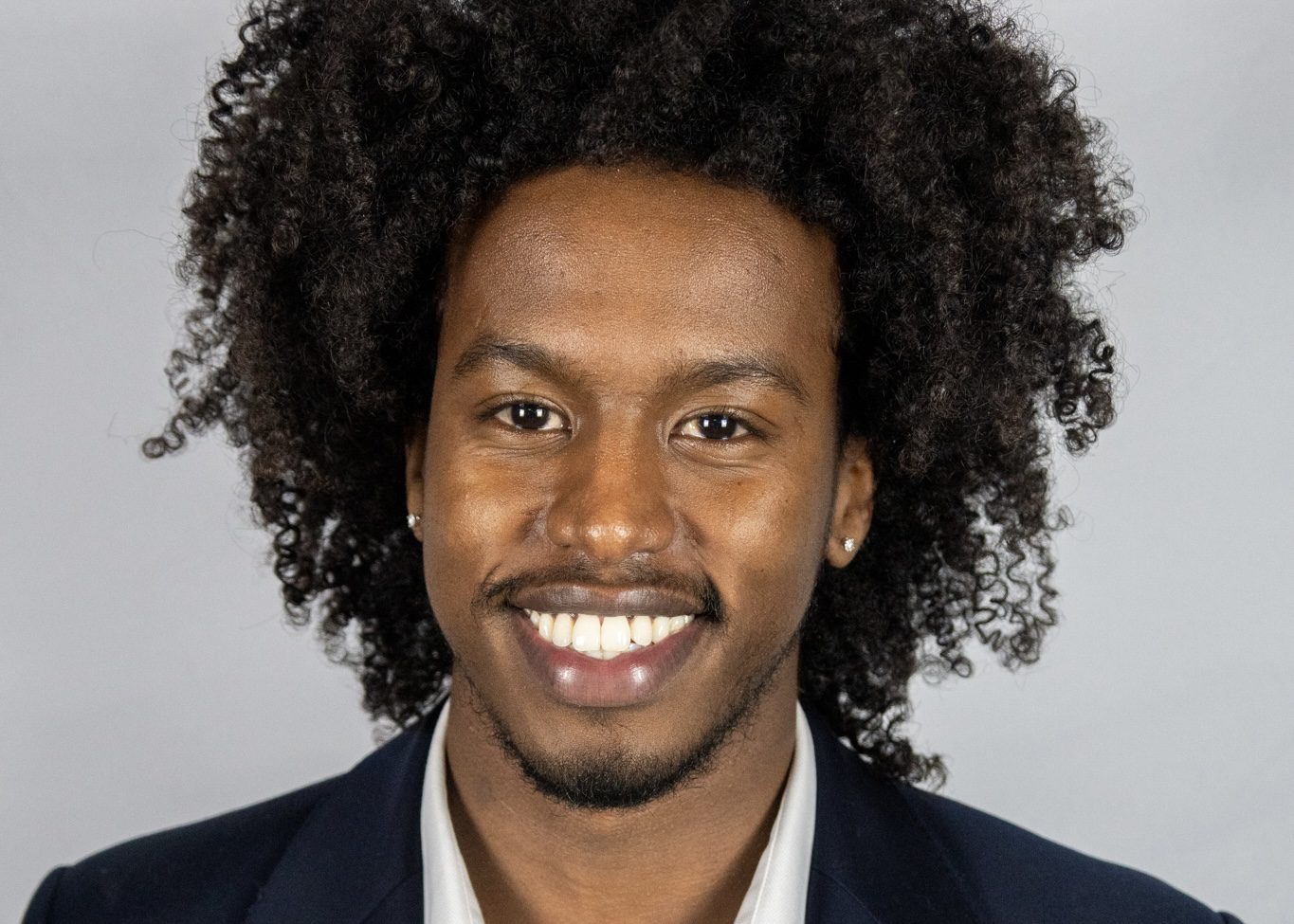 Faid, wearing a black suit, smiles.