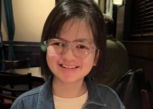 Andrea, wearing glasses, smiles at the camera.