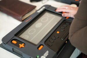 An adult hand sits on the Monarch navigation keys, while a graphic of circles is displayed on the screen.