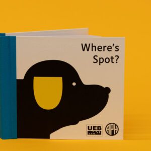 Where's Spot? storybook placed upright on a yellow background. On the cover is the title and a black dog with a yellow ear with the UEB and APH logos in the bottom right corner.