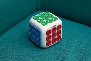 Creacube with the red buttons facing forward sitting on top of the yellow and blue box.