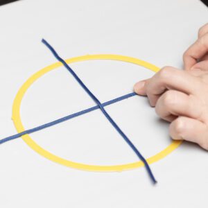 A hand exploring a tactile yellow circle placed on an AnyMath board with blue line strips dividing the circle into fourths.